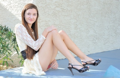 Skinny teen girl gives a naked upskirt view and spreads naked pussy outdoors