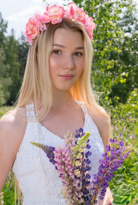 Young blonde wears a crown of flowers during her nude debut amid fireweed