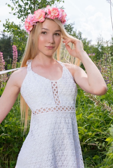 Young blonde wears a crown of flowers during her nude debut amid fireweed