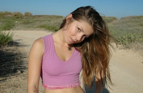 Young girl frolics on a dirt road well wearing a denim miniskirt and a thong