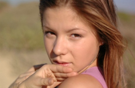 Young girl frolics on a dirt road well wearing a denim miniskirt and a thong