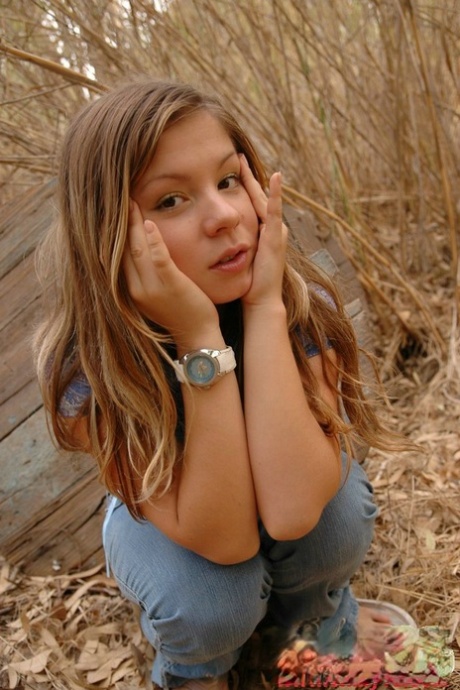 Adorable young girl shows her firm tits amid bushes in cute panties