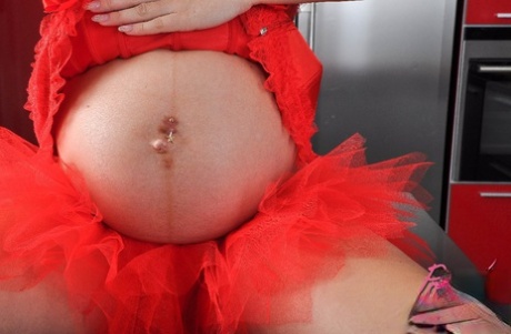 Pregnant girl gets naked on a kitchen counter in a tutu and high-heeled shoes