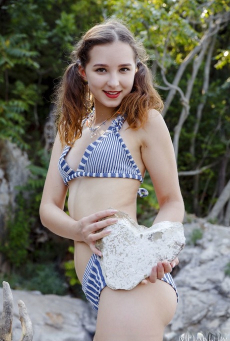 Sweet teen Ava sports red lips while doffing a bikini to go naked by the water