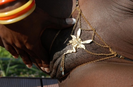 Dark chocolate skinned female shows the pink of her twat during closeup action