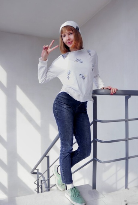 Young looking girl Dream sports red lips while getting undressed