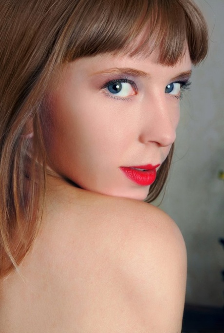 Young looking girl Dream sports red lips while getting undressed
