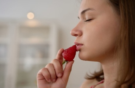 Young girl Yenn Cat gets totally naked while eating strawberries in a kitchen