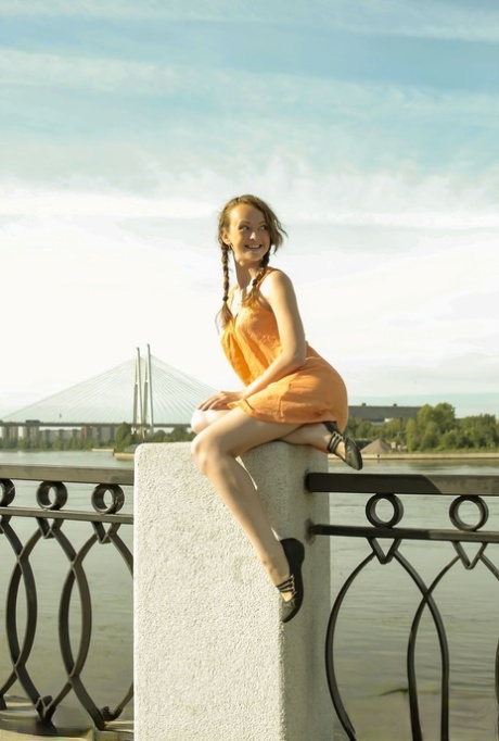Charming teen Vega tugs on her pigtails before going nude next to the water