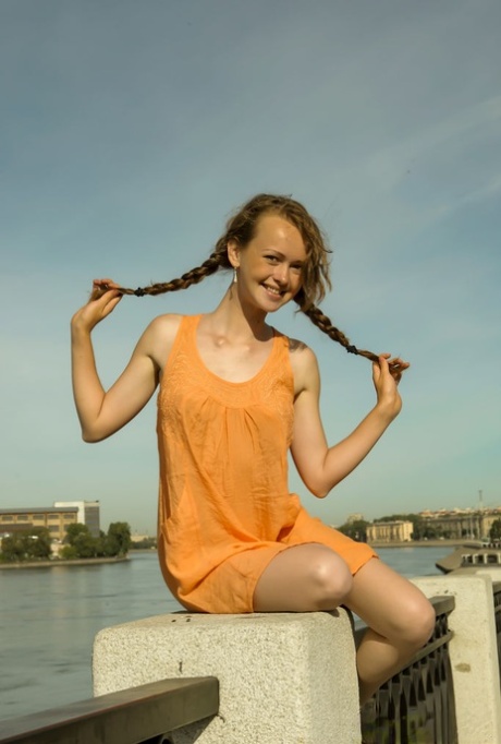Charming teen Vega tugs on her pigtails before going nude next to the water