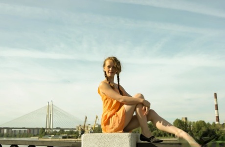 Charming teen Vega tugs on her pigtails before going nude next to the water