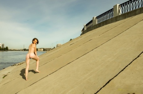 Charming teen Vega tugs on her pigtails before going nude next to the water