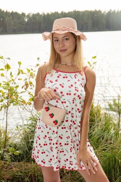 Adorable blonde teen Aura frees her tan lined body next to a lake