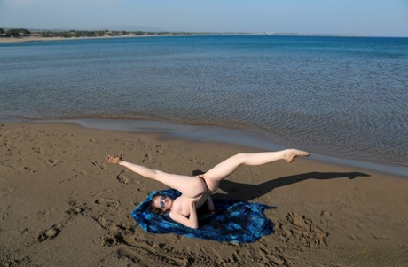 Beach beauty Emily sunbathing naked on the sand spreading long legs wide open