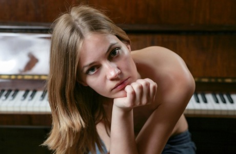 Glamorous teen babe Frosiya strips off her stockings in front of the piano