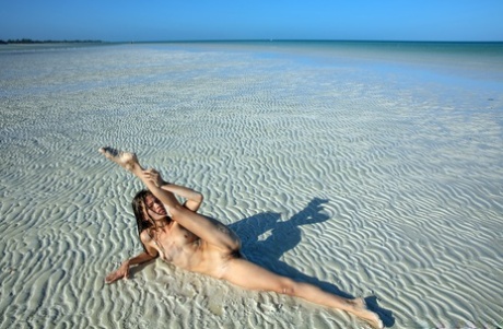 Sweet teen Irene Rouse spreads her slim legs and poses naked on the beach