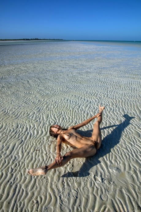 Sweet teen Irene Rouse spreads her slim legs and poses naked on the beach