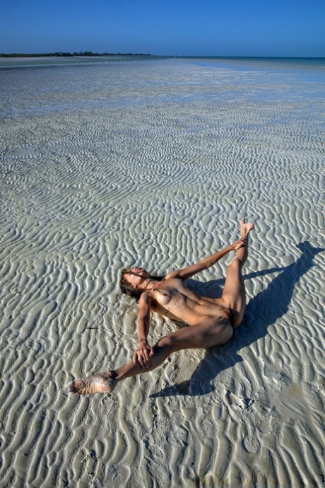 Sweet teen Irene Rouse spreads her slim legs and poses naked on the beach