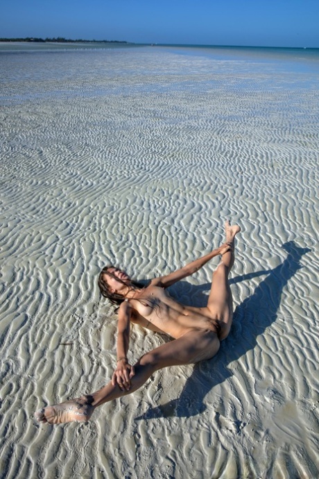 Sweet teen Irene Rouse spreads her slim legs and poses naked on the beach